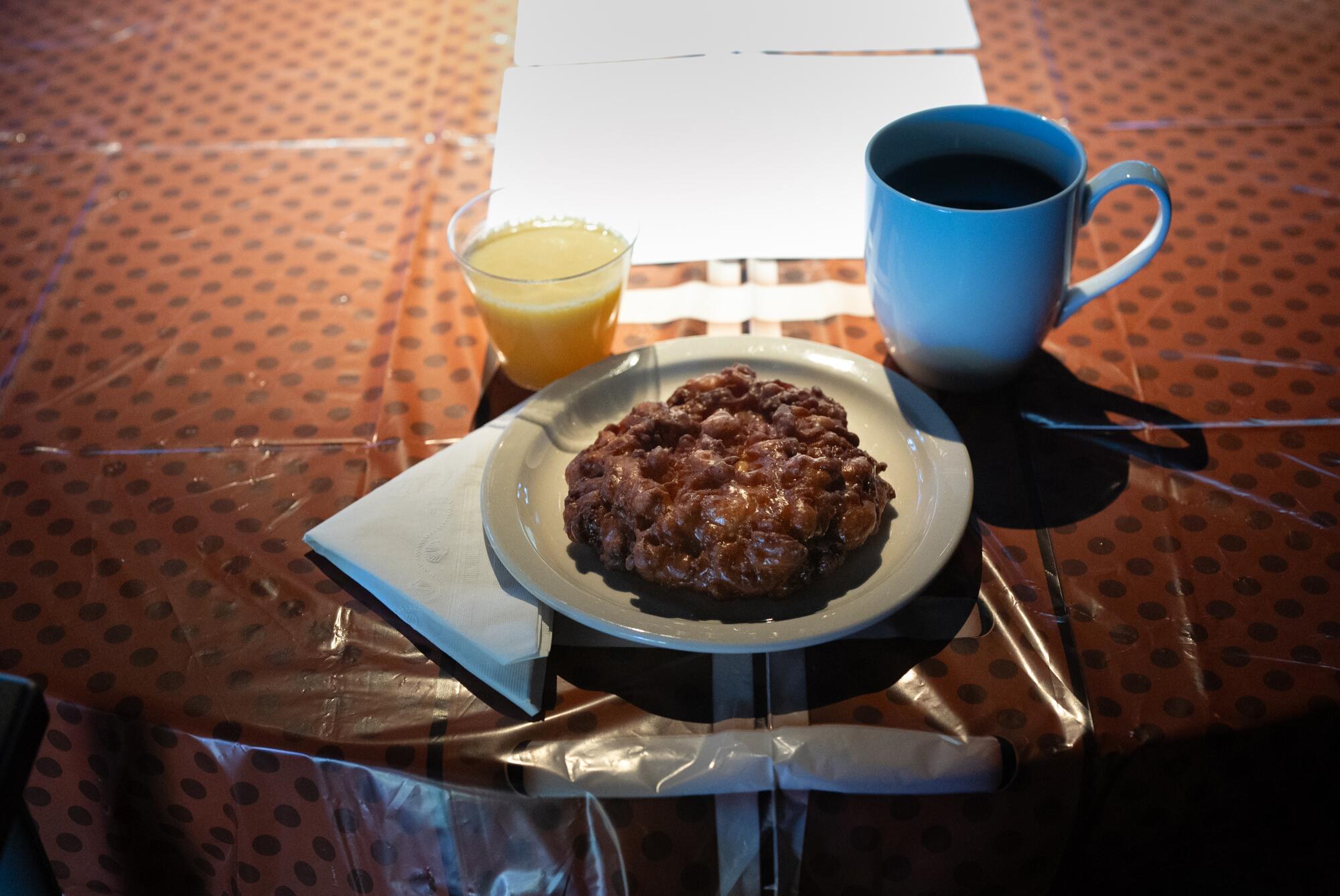 A coffee cup, orange juice and pastry on a table.