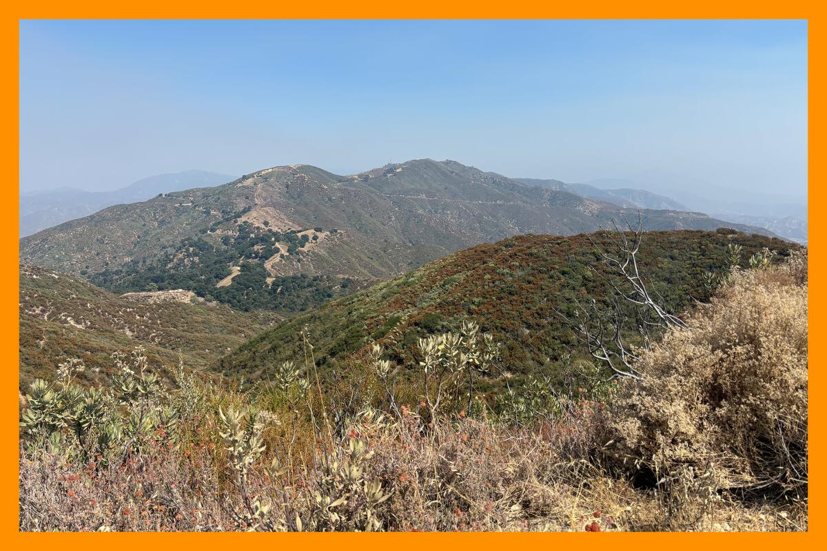 Brown/green hills stretch far into the hazy distance.