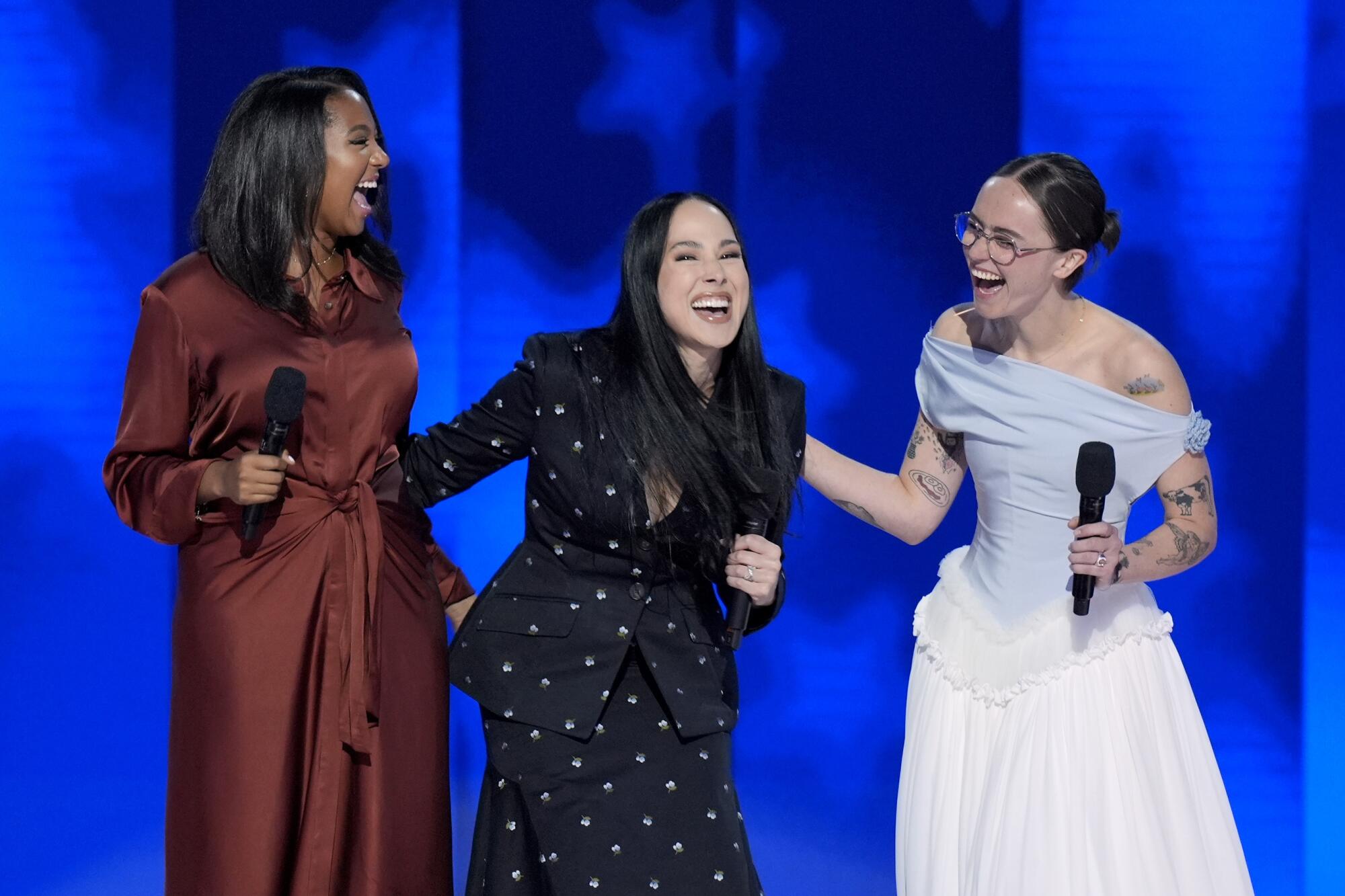 Helena Hudlin, left, Meena Harris and Ella Emhoff smiling onstage at the DNC