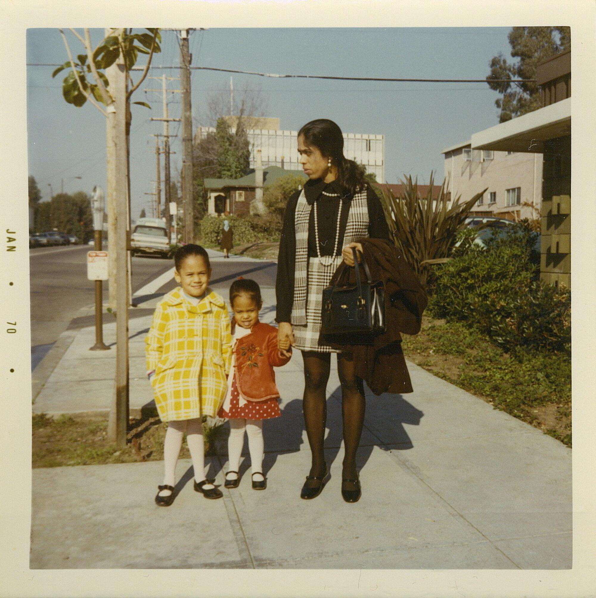 A vintage photo of Kamala Harris, Maya Harris and their mother Shyamala Gopalan on a city sidewalk