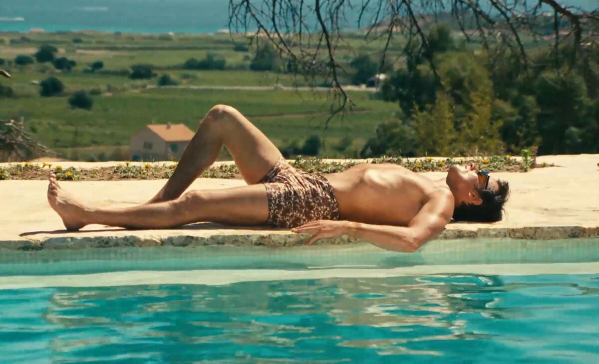 A man tans by a swimming pool.