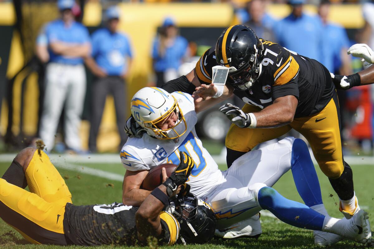 The Chargers' Justin Herbert is sacked by Elandon Roberts and Cameron Heyward