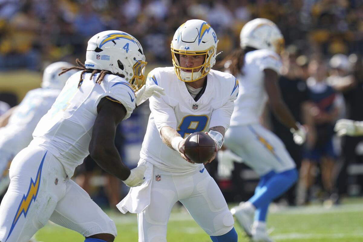 Chargers quarterback Taylor Heinicke hands the ball off to running back Gus Edwards