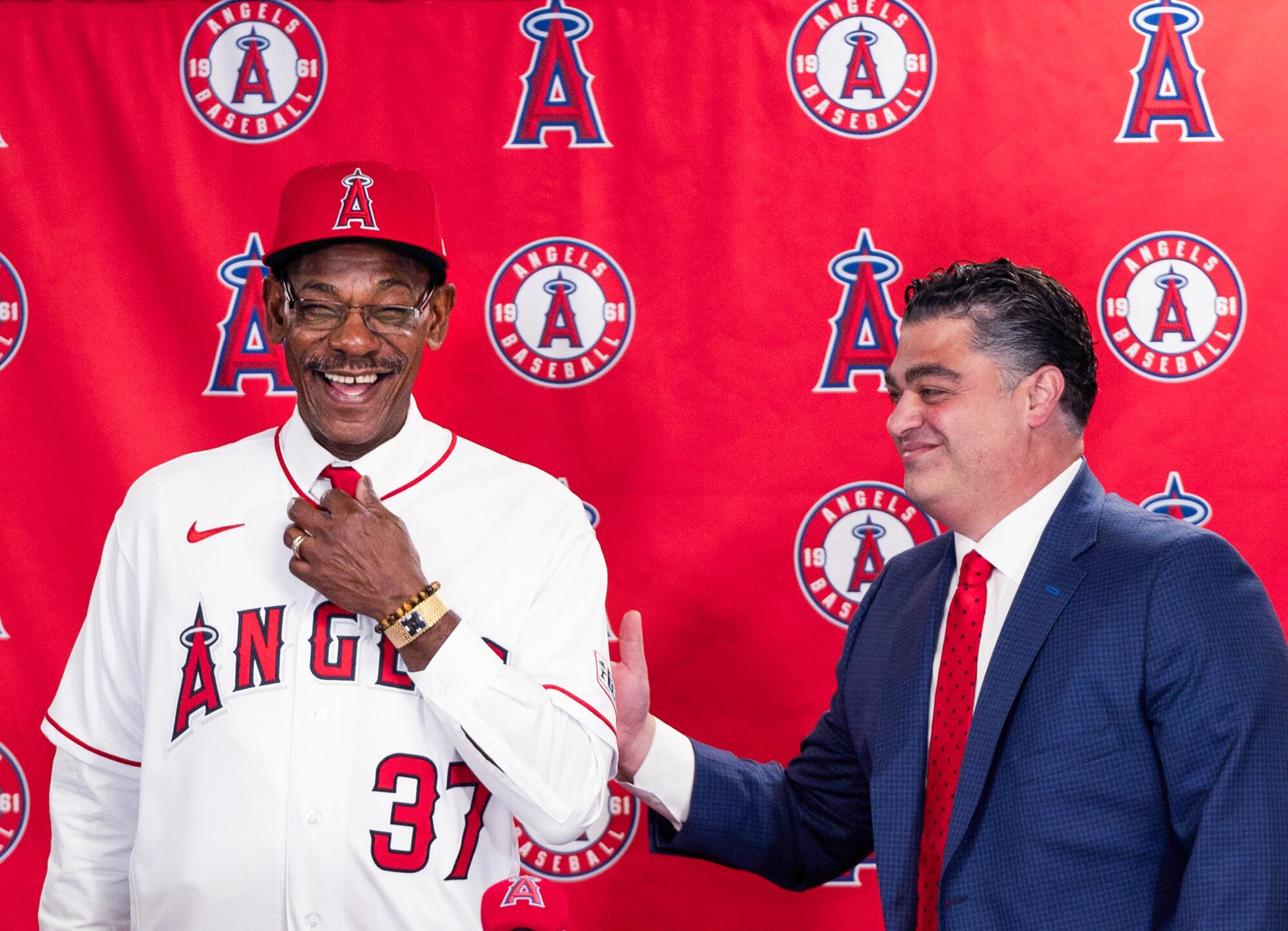 Angels general manager Perry Minasian taps manager Ron Washington's arm during a news conference.