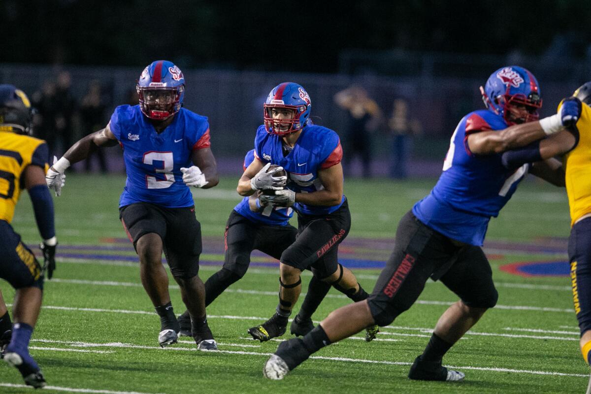 Kai Honda (center) looks for room to run after taking a handoff while playing at Gardena Serra in 2022.