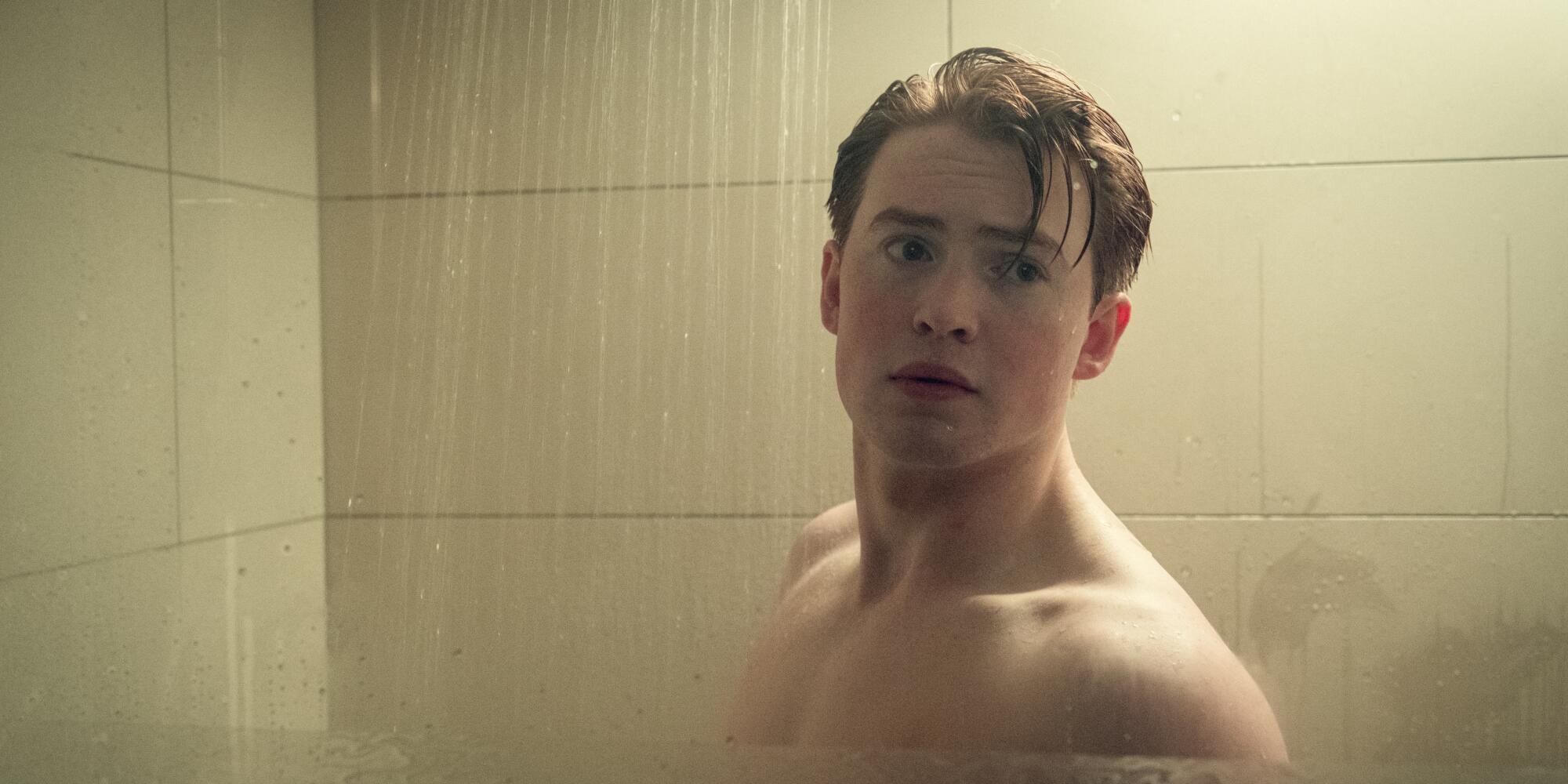 A shirtless man standing in a shower stall.