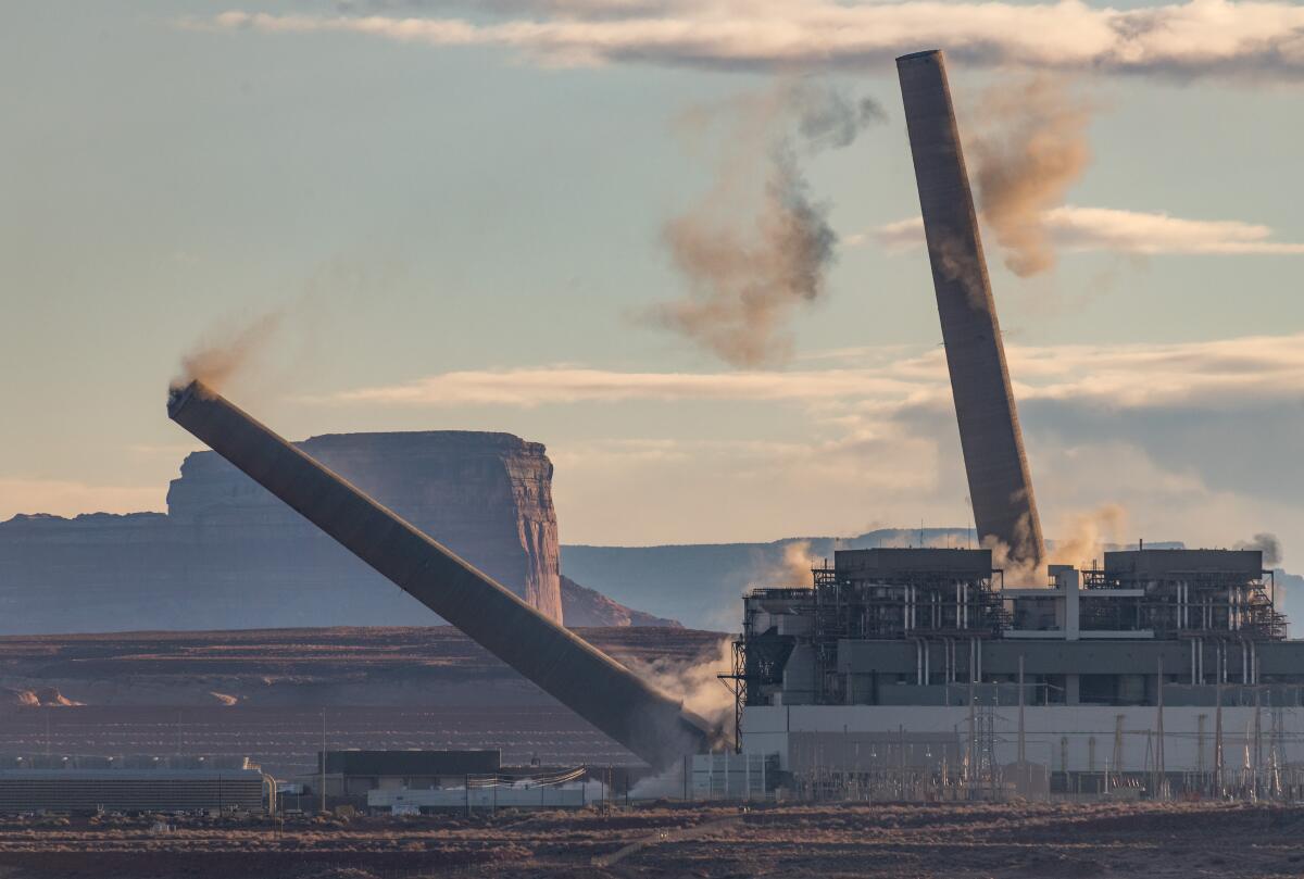 Two of the three coal smokestacks at Navajo Generating Station outside Page, Ariz., come tumbling down in 2020.