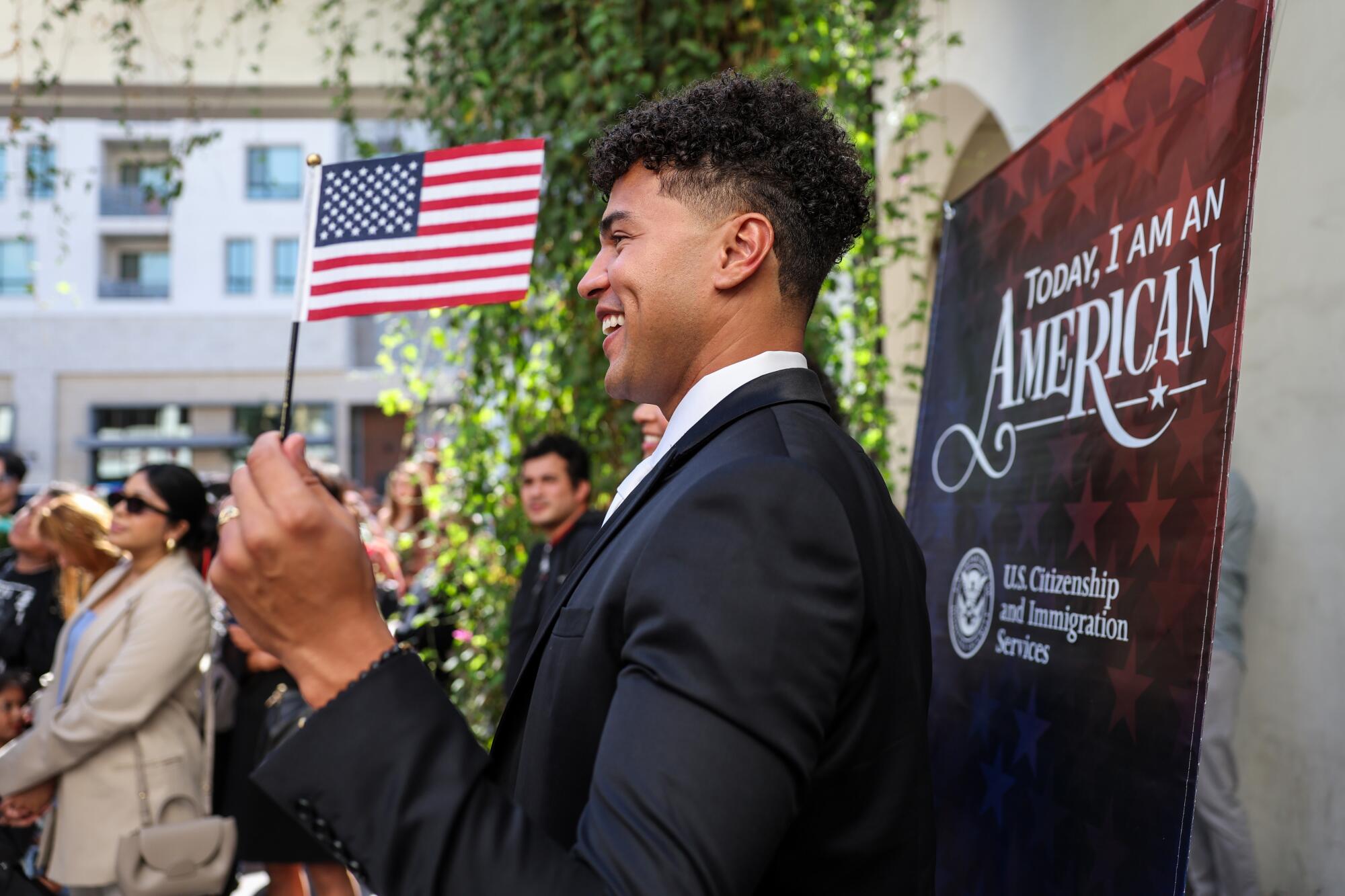 A smiling man raises a small American flag.