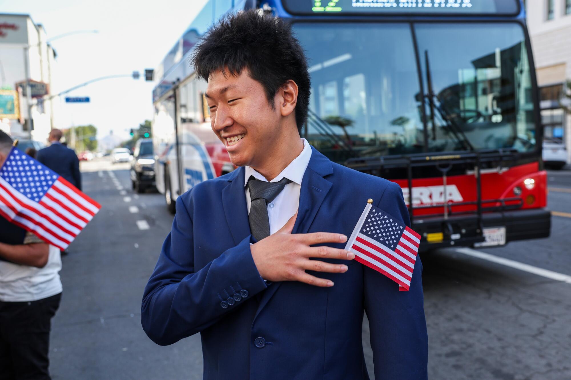 A man who has a small American flag in his suit jacket's pocket smiles.