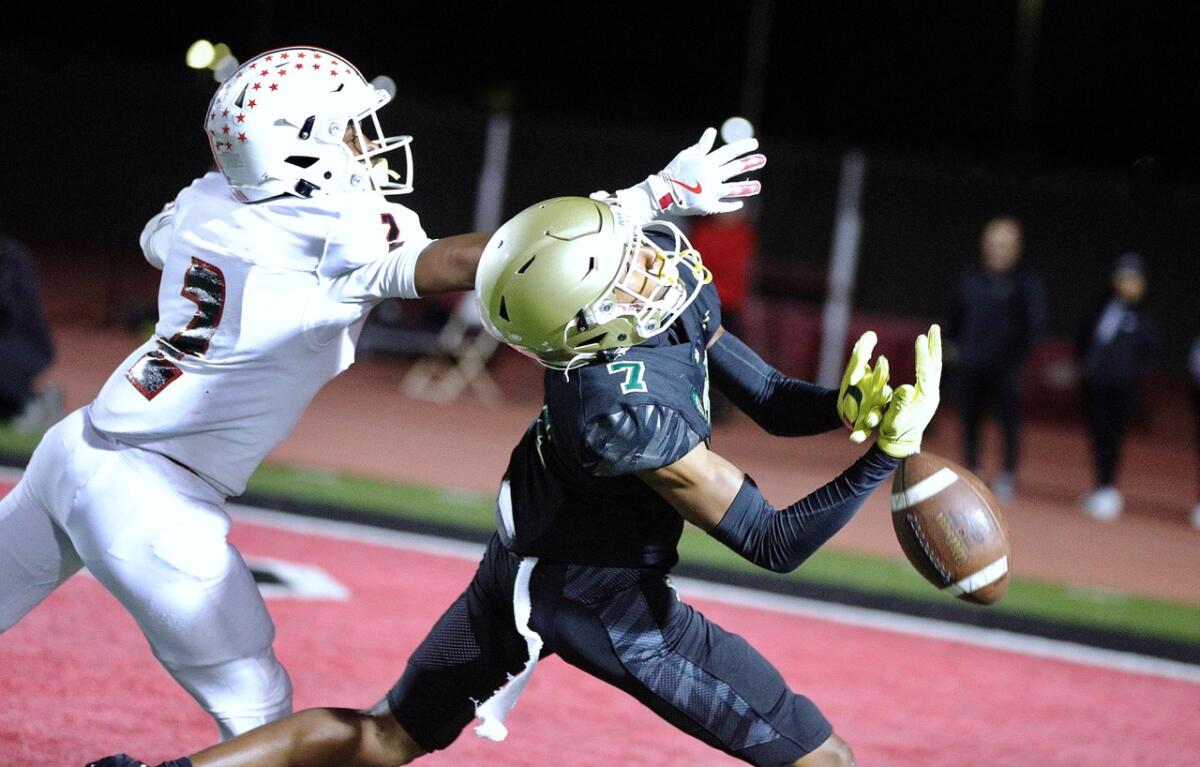 Long Beach Poly receiver Dylin Bruce, right, tries to make a catch in the end zone as Lakewood’s Tiwan Jones defends.