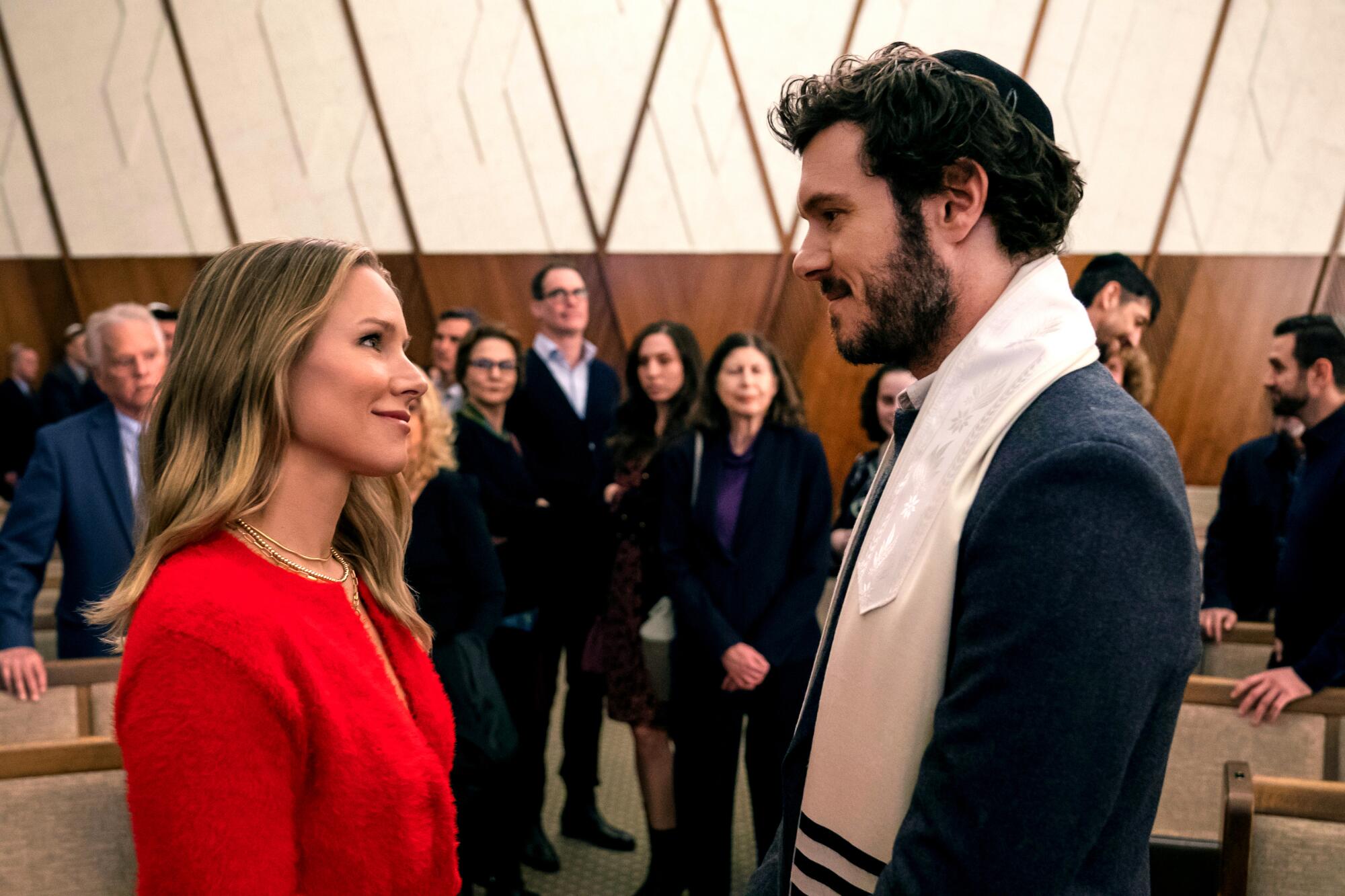 A woman in red stares at a rabbi wearing a tallit and yarmulke