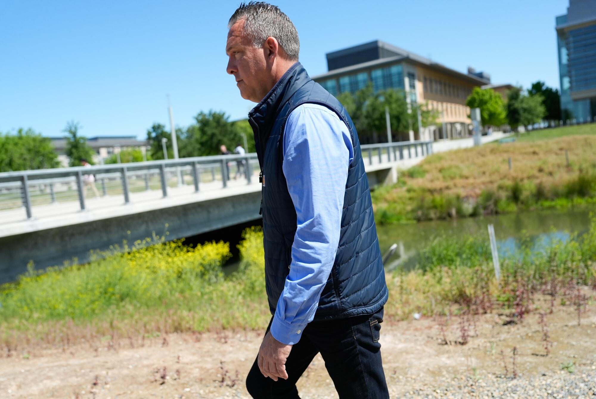 Adam Gray, wearing a blue down vest, walks on the UC Merced campus. 