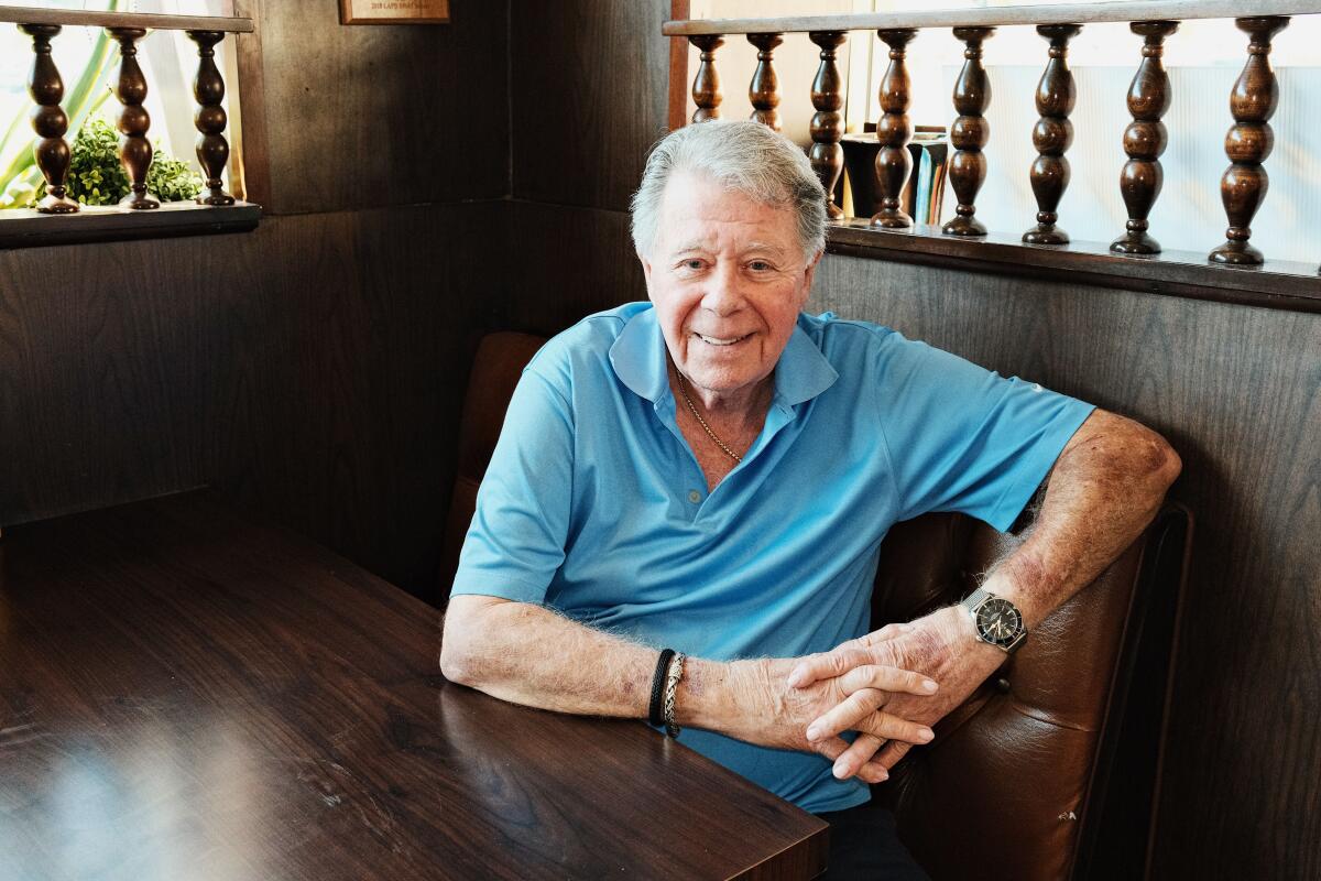 Norm Langer sits in a wooden booth, looking at camera, inside Langer's Delicatessen-Restaurant in Westlake.