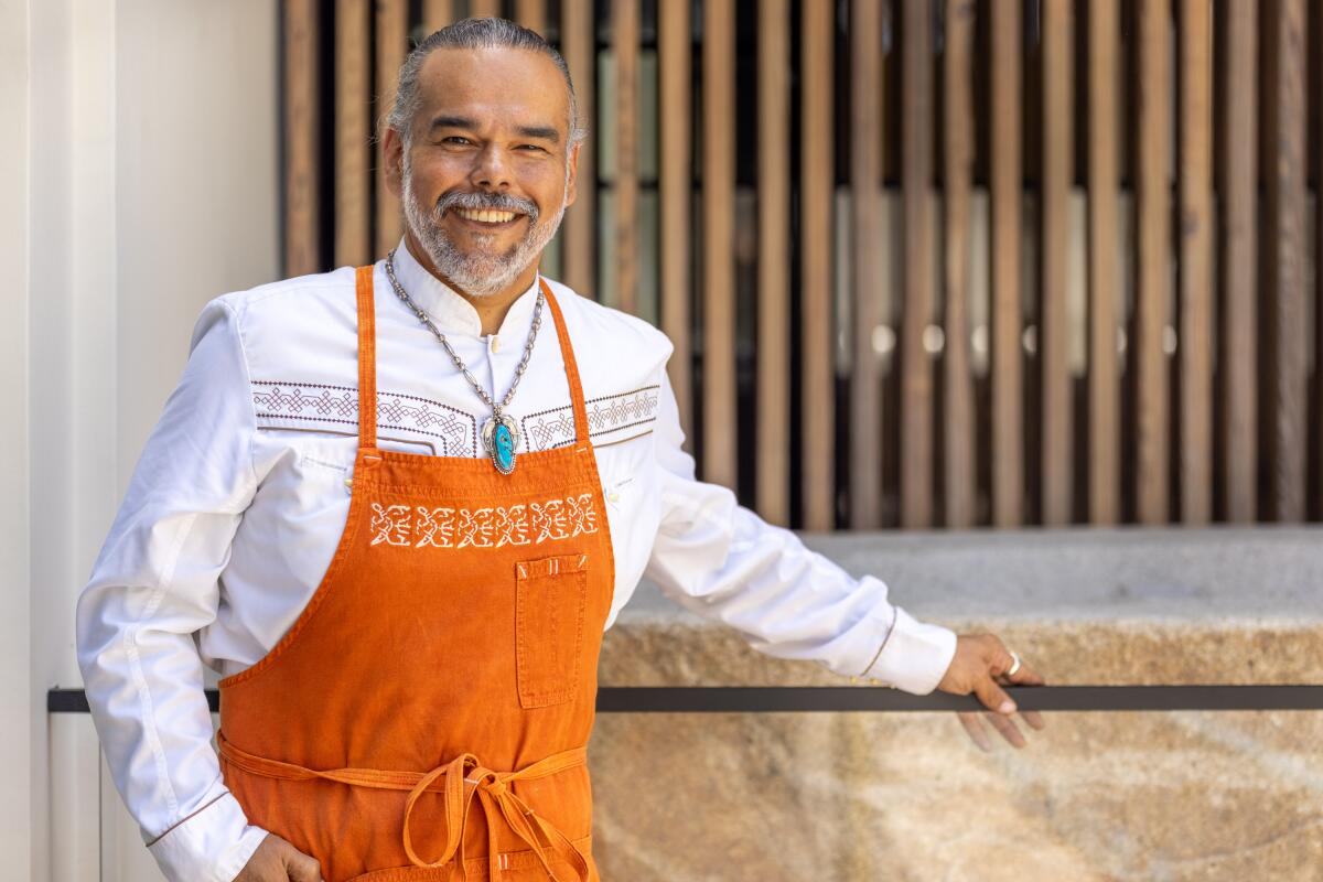 Wes Avila, chef-owner of Mexican steakhouse MXO, stands smiling in orange apron