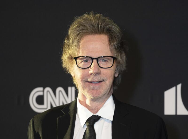 A man in black rimmed glasses in a dark suit and tie.