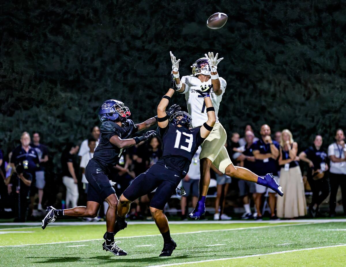 St. John Bosco's Madden Williams leaps to make a catch between two Sierra Canyon defenders for a 45-yard gain.