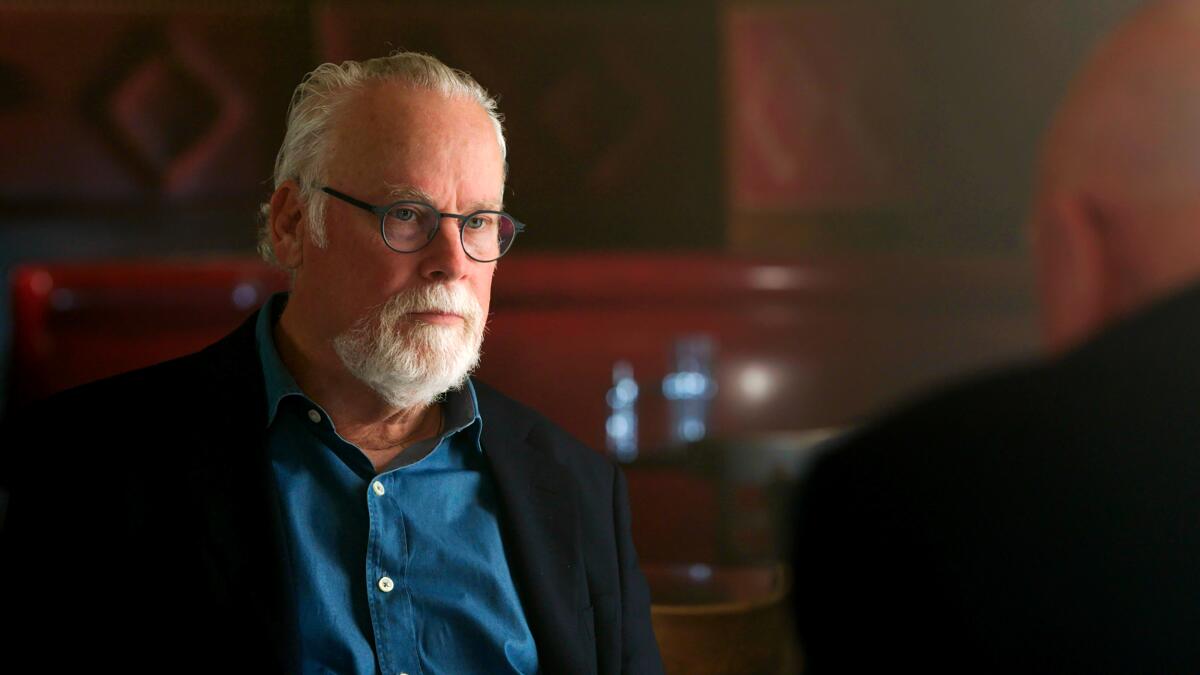 A man in glasses with a white hair and beard looks intently.