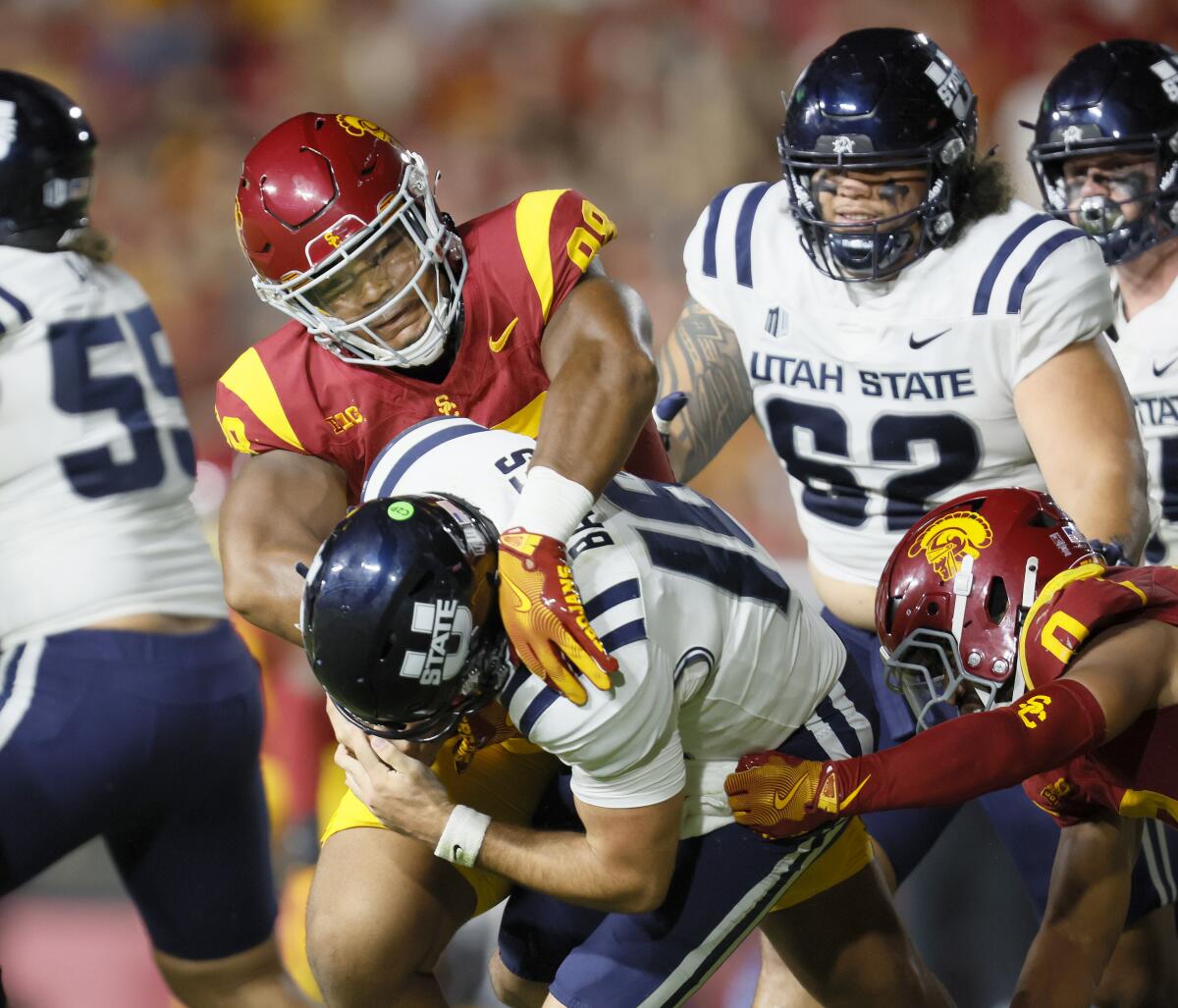 USC defensive end Devan Thompkins, left, sacks Utah State quarterback Bryson Barnes with help from Akili Arnold. 