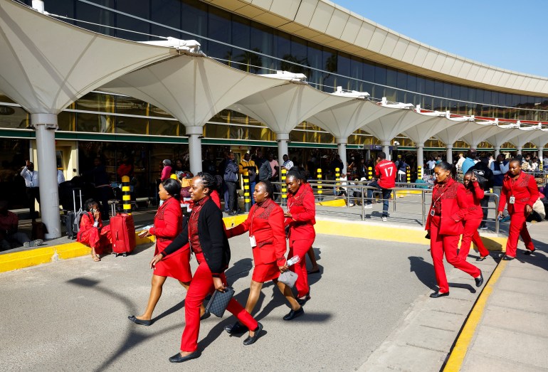 Kenya Airways workers walk past passengers waiting for their flights during a strike by Kenya airports union workers to protest against a proposed deal for India's Adani Group ADEL.NS, to lease Jomo Kenyatta International Airport (JKIA) for 30 years, in Nairobi, Kenya September 11, 2024. REUTERS/Thomas Mukoya