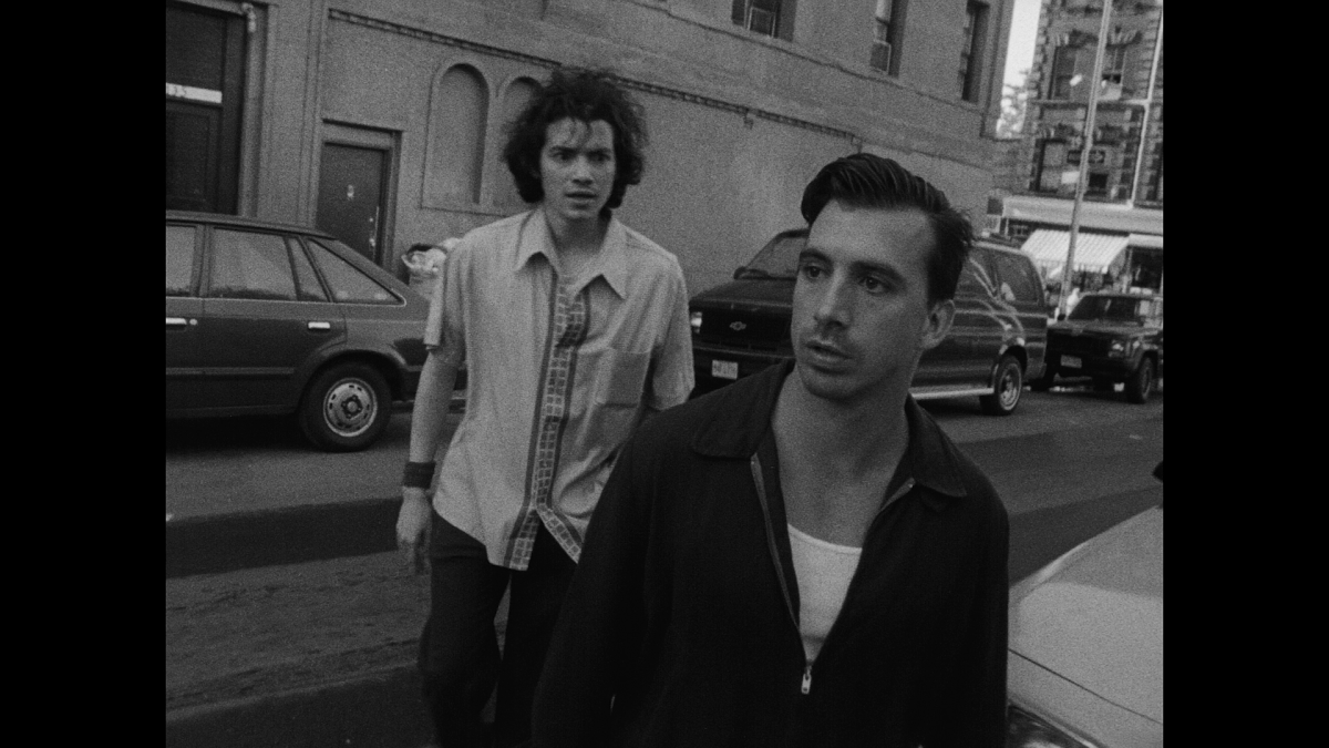 Two men stand in the street.