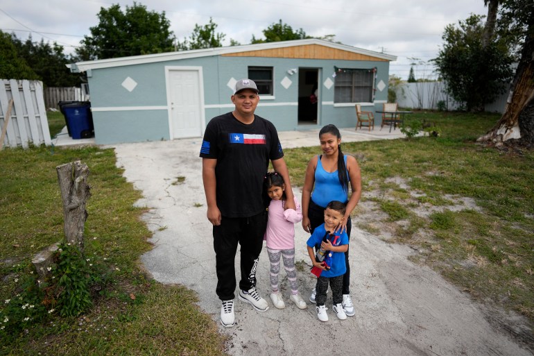 The Llanos family is among the first allowed into the United States under the "Safe Mobility Initiative." The family stands in front of a low-slung house.