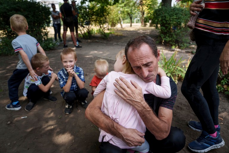 A father hugs his daughter, his other children nearby, as they wait for evacuation in Pokrovsk, Donetsk region, Ukraine, Friday, Aug. 23, 2024. (AP Photo/Evgeniy Maloletka)