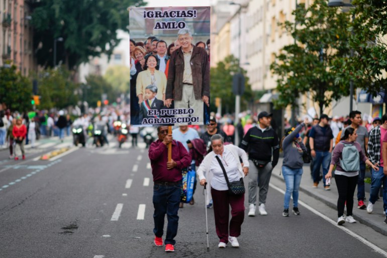 People walk to listen to Lopez Obrador speak