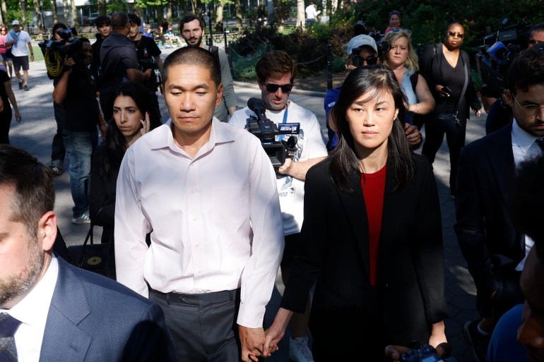 Linda Sun and her husband Christopher Sun walk outside a court, surrounded by press