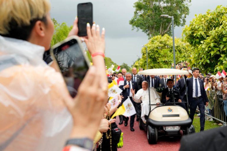 Pope Francis travels in a buggy as he greets the volunteers on his arrival in Singapore