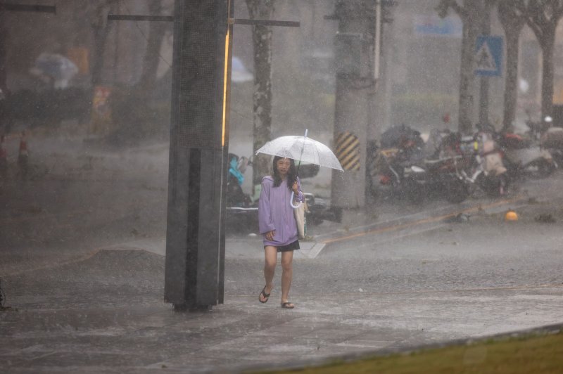 A woman in downtown Shanghai on Monday braves lashing rain and winds from Typhoon Bebinca which caused widespread damage and dumped 10 inches of rain after scoring a direct hit on China's financial capital overnight. Photo by Alex Plavevski/EPA-EFE