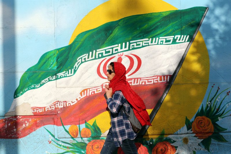 An Iranian walks next to a wall painting of Iran's national flag at a street in Tehran, Iran, on June 2, 2022. Canada on Sunday expanded its list of Iranian government officials who are not admissible to the country. File Photo by Abedin Tahereknareh/EPA-EFE