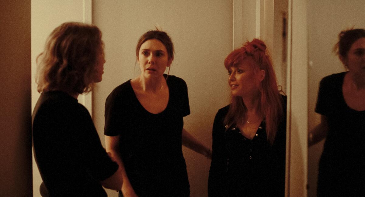 Three women talk animatedly in a hallway in 'His Three Daughters.'