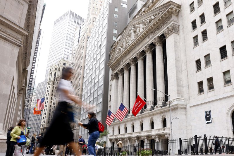 Pedestrians walk near the New York Stock Exchange in New York City on Wednesday as the Federal Reserve Board announced its first interest rate cut in four years. On Friday the Dow Jones Industrial Average finished the week in record-high territory. Photo by John Angelillo/UPI