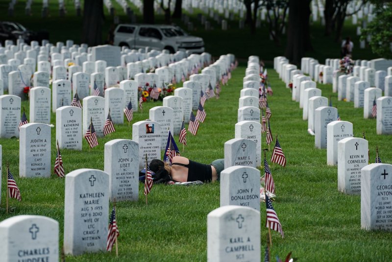 A woman lays at the grave of a fallen marine as she pays her respects at Arlington National Cemeteries Section 60 on May 29, 2022. Former President Donald Trump appeared there on Monday in what Vice President Kamala Harris described as a "political stunt." File photo by Jemal Countess/UPI