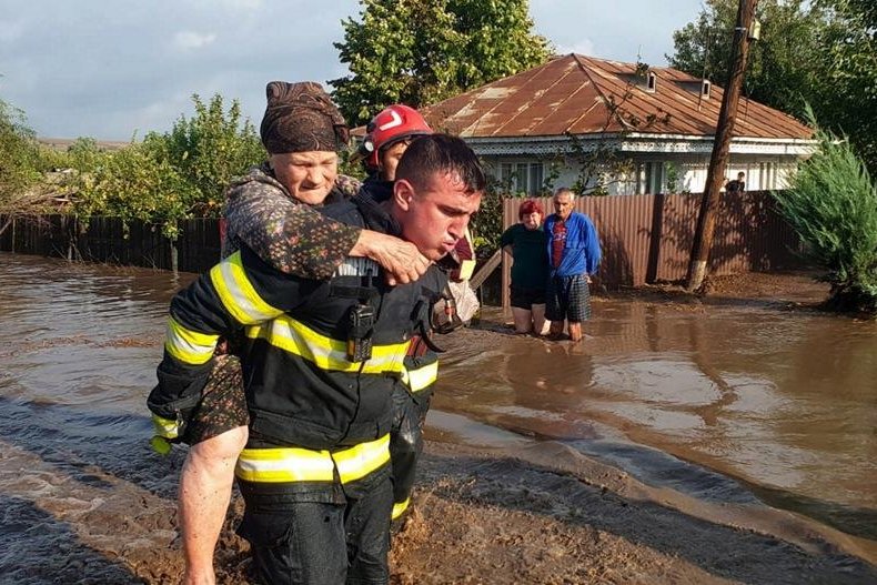 A first responder helps an elderly woman reach safety as heavy rainfalls inundate Romania and other parts of Europe with flooding that killed at least four in Romania. Photo by the Romanian General Inspectorate for Emergency Situations/EPA-EFE