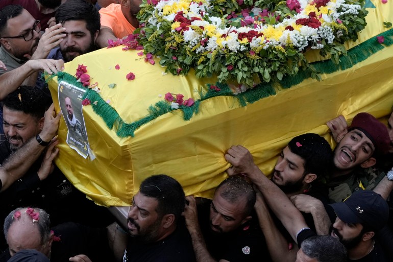 Hezbollah fighters carry one of the coffins of four fallen comrades.