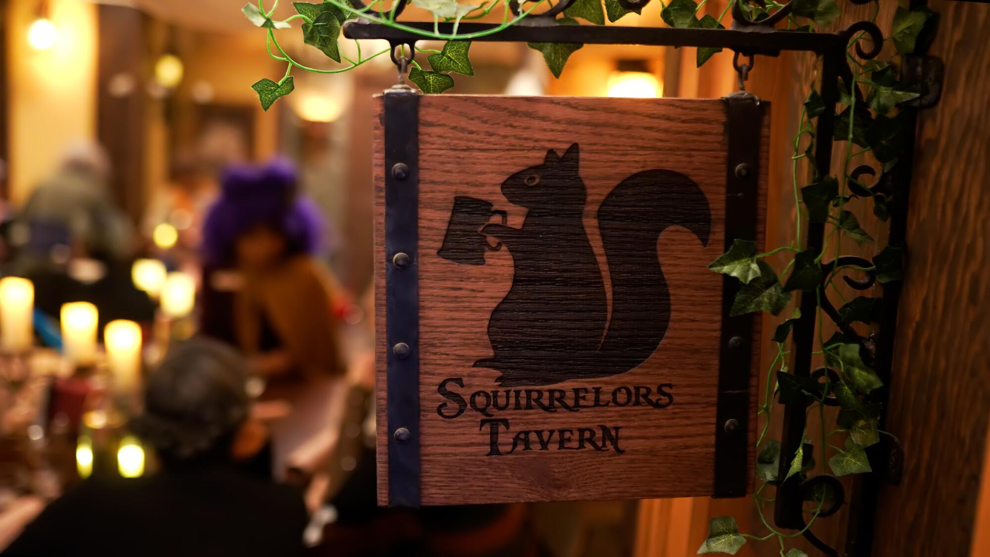 A wooden Squirrelor's Tavern sign bears a squirrel holding a pint glass. 