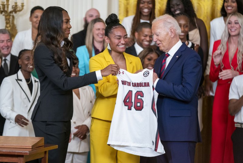 President Joe Biden accepts a jersey from Te-Hina Paopao (C), and Bree Hall (L) during a ceremony to celebrate the 38-0 University of South Carolina Gamecocks' 2023-2024 NCAA championship season, in the East Room of the White House on Tuesday. Photo by Shawn Thew/UPI