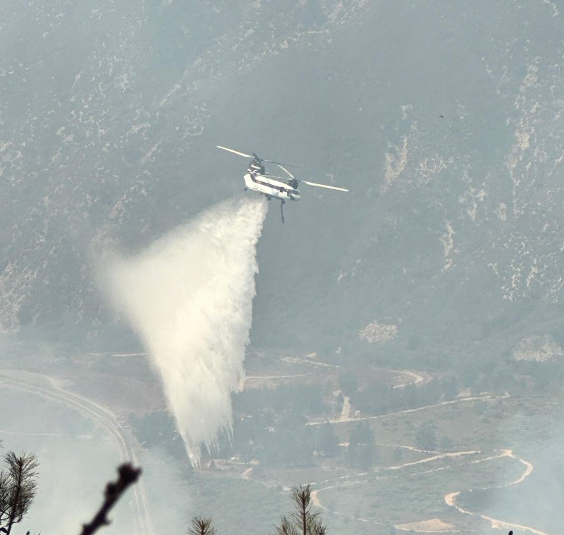 A helicopter doses the Line Fire in San Bernardino County, Calif., on Tuesday as the blaze threatens tens of thousands of structures. Photo courtesy of Cal Fire San Bernardino Unit Public Information Office/X