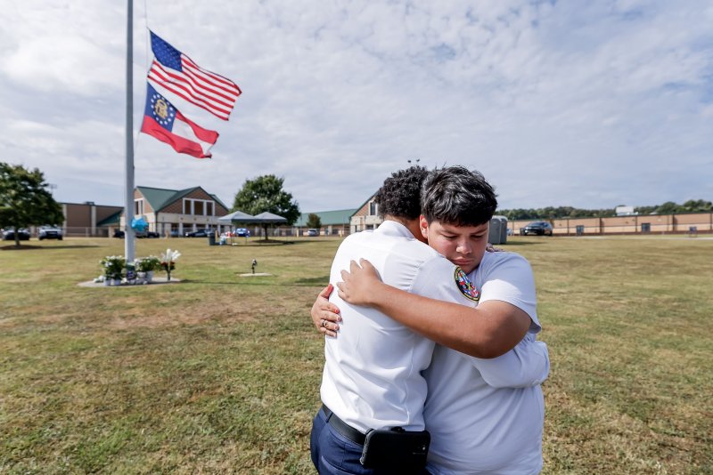 Fourteen-year-old student Jose Ortiz accepts an embrace from chaplain Ronald Clark at a makeshift memorial on Sept. 5, one day after a deadly school shooting at Apalachee High School in Winder, Ga. Photo by Erik S. Lesser/EPA-EFE