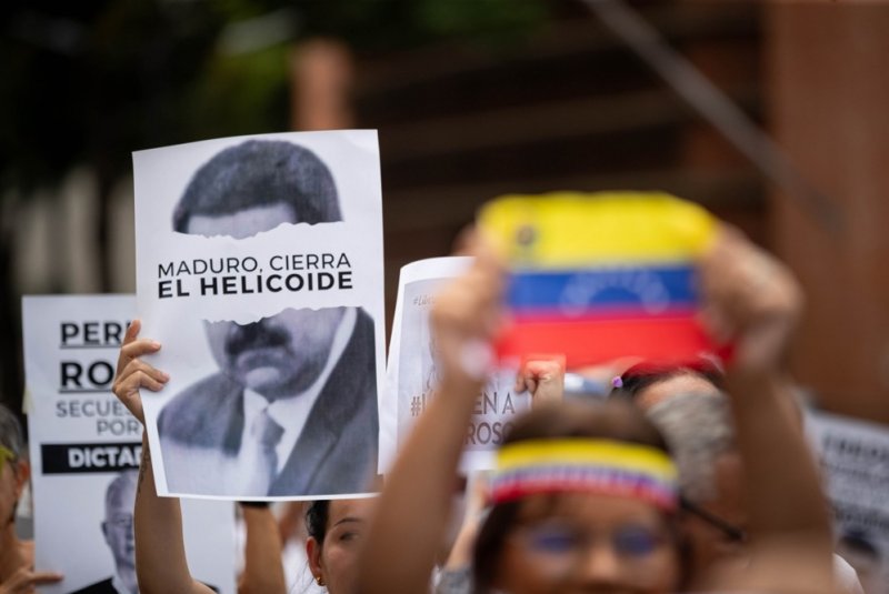 A man holds a sign with the image of Venezuelan President Nicolás Maduro and text that reads: "Maduro, close the (Centro Penitenciario El Helicoide)" during a protest by the families of political prisoners demanding their release in Caracas, Venezuela, on September 11. Photo by Ronald Pena Jr./EPA-EFE