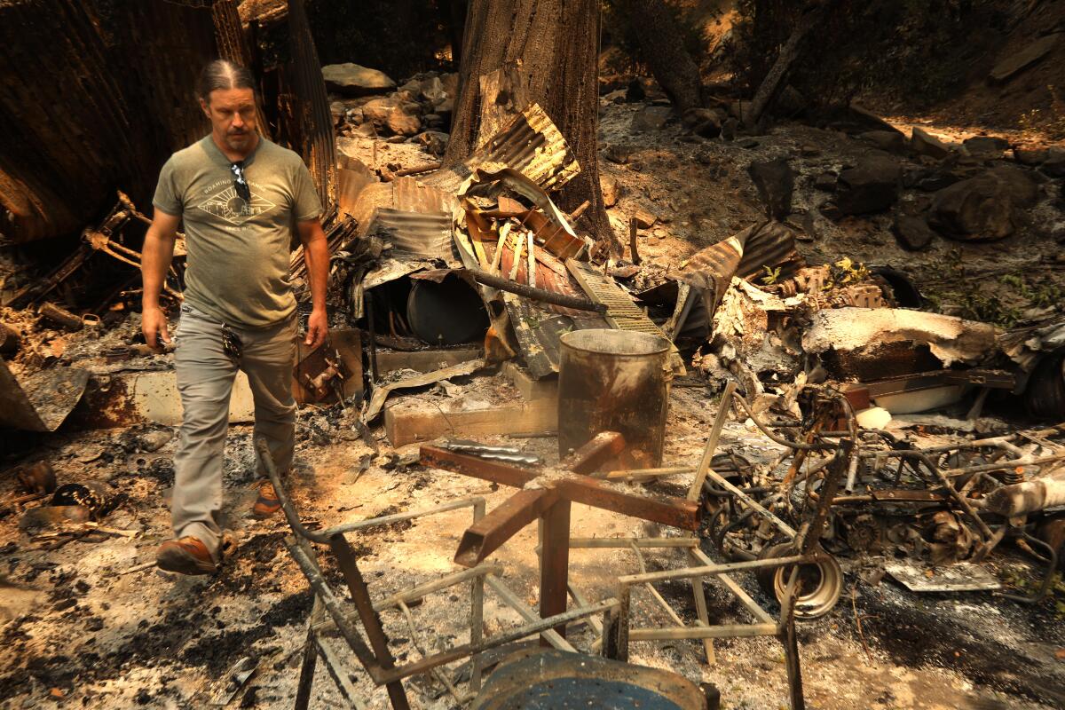 David Mix walks through the ruins of his cabin that was destroyed in the Bridge fire along Bear Canyon Road in Mount Baldy.