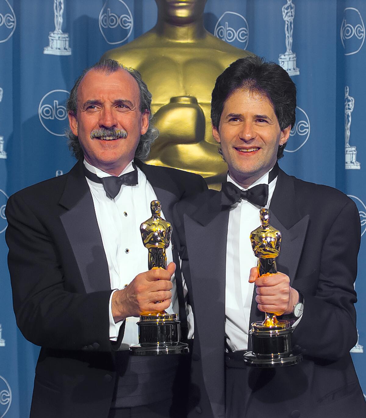 Two men holding statuettes