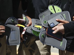 FILE - A student uses their cell phone after unlocking the pouch that secures it from use during the school day at Bayside Academy, Aug. 16, 2024, in San Mateo, Calif.