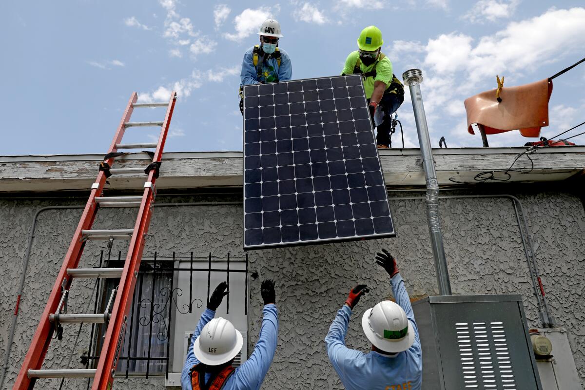 Workers install rooftop solar panels