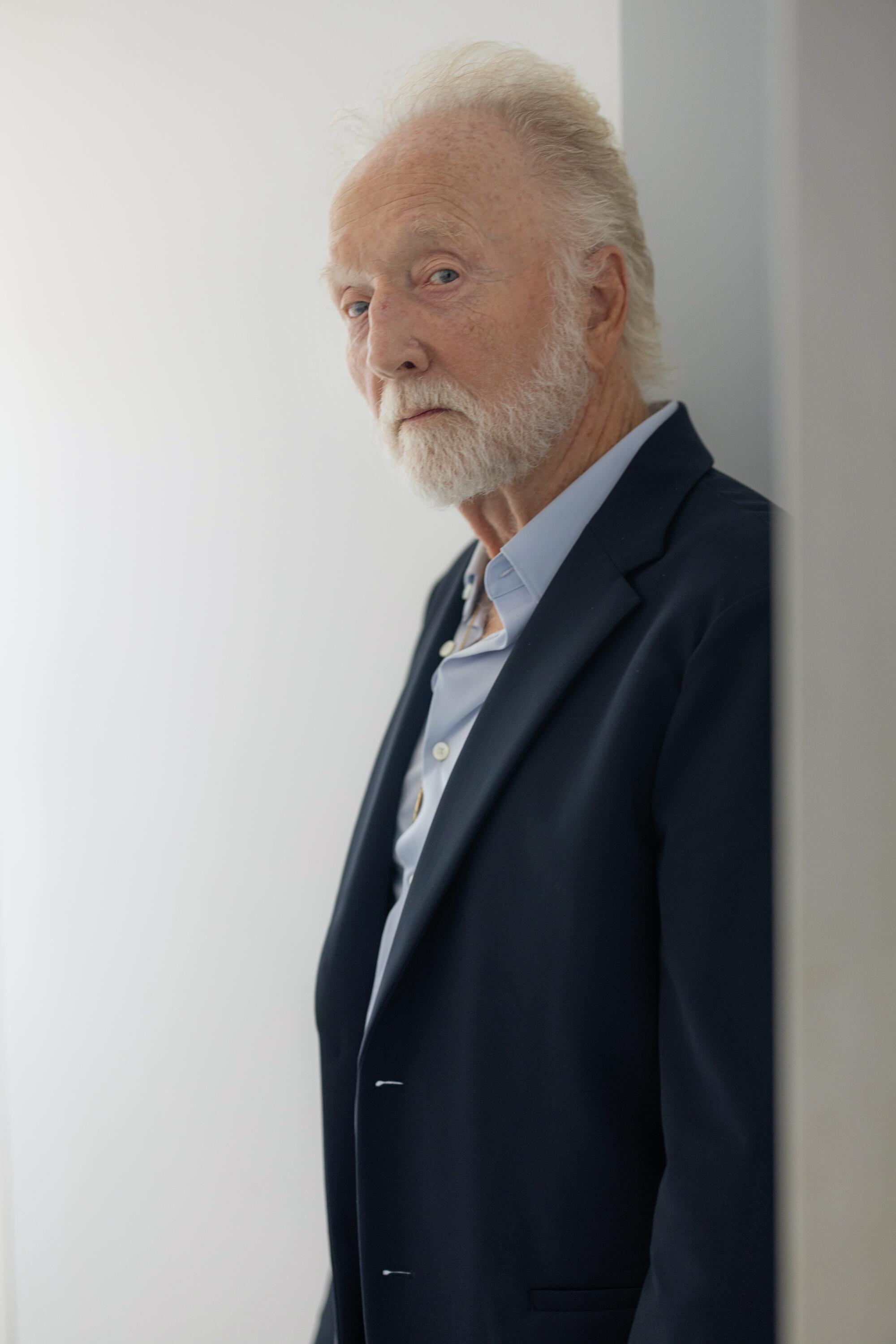 A man in a dark blazer gazes calmly.