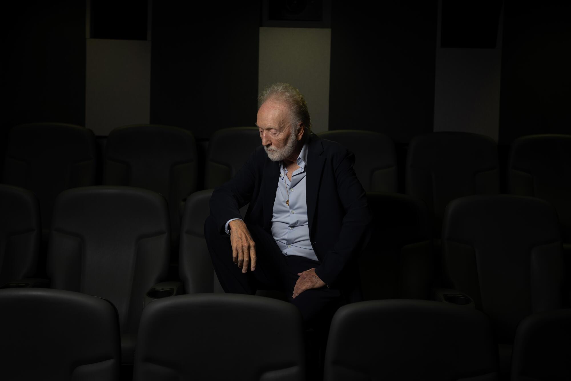 A man sits in an empty auditorium.