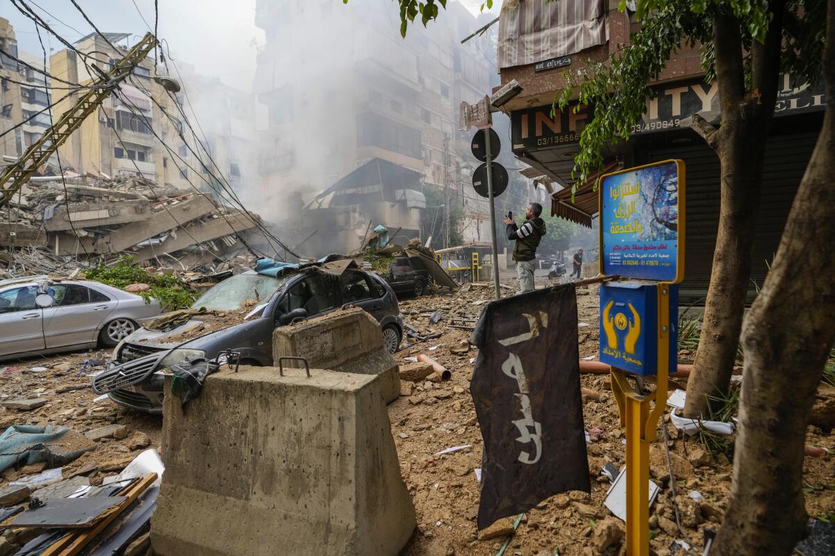 A man documents the damaged buildings at the site of an Israeli airstrike in Beirut's southern suburb on Oct. 1.