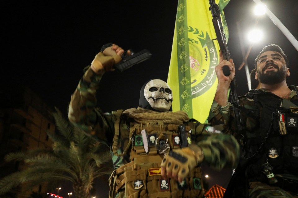 Iran-backed shi'ite militant fighters celebrate on a street following the attack on Israel