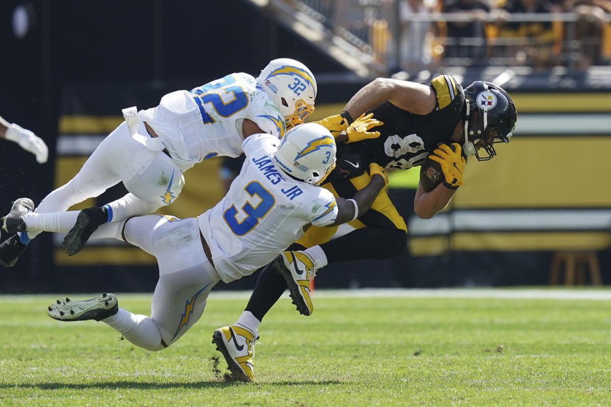 Chargers safeties Alohi Gilman (32) and Derwin James Jr. tackle 6-foot-5 Steelers tight end Pat Freiermuth.